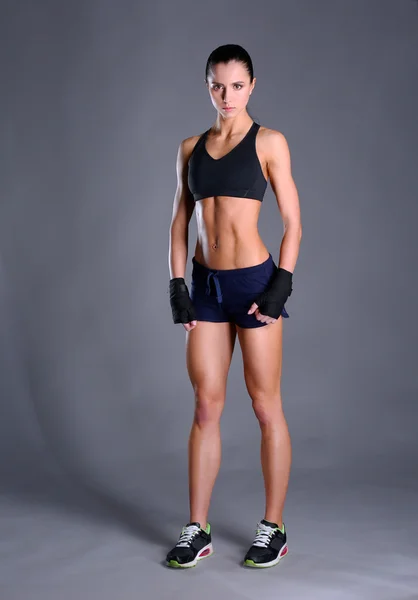 肌肉构成的运动服在黑色背景下的年轻女子 — 图库照片