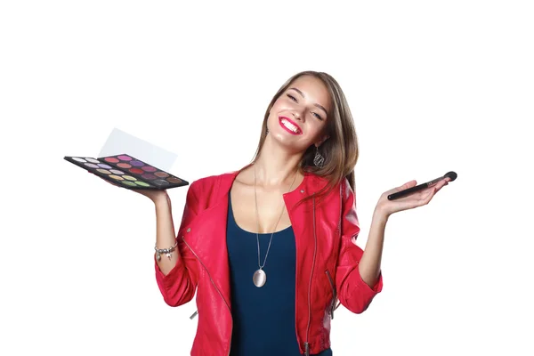 Young beautiful woman holds in one hand and a palette with paint and shadows for makeup, second hand brush for makeup — Stock Photo, Image