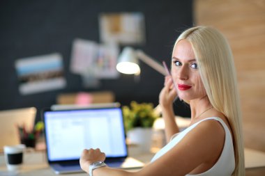 Moda tasarımcıları stüdyoda çalışıyor. Masanın üzerinde oturuyorlar.