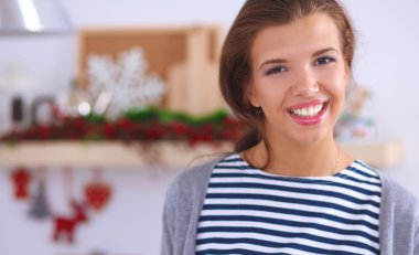 Mutfakta gülümseyen genç bir kadın, Noel arkaplanında soyutlanmış.