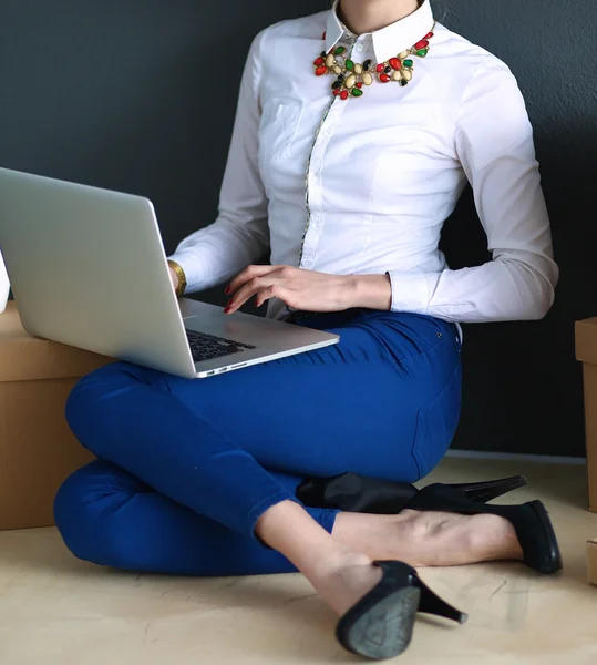 Kadın yerde dizüstü bilgisayarlı bir kutunun yanında oturuyor. — Stok fotoğraf