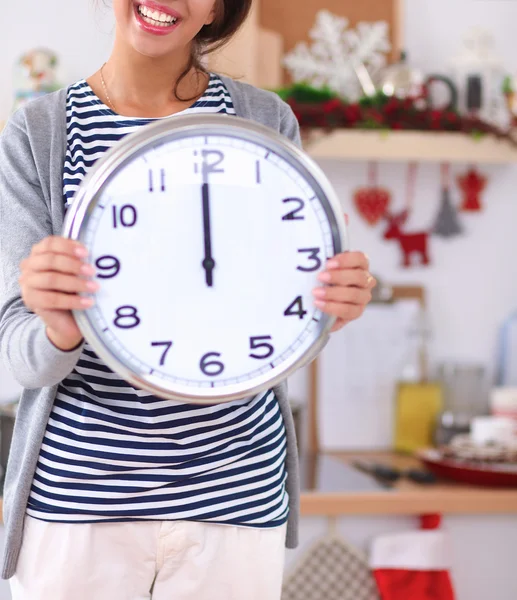 Gelukkig jong vrouw tonen klok in kerst versierd keuken — Stockfoto