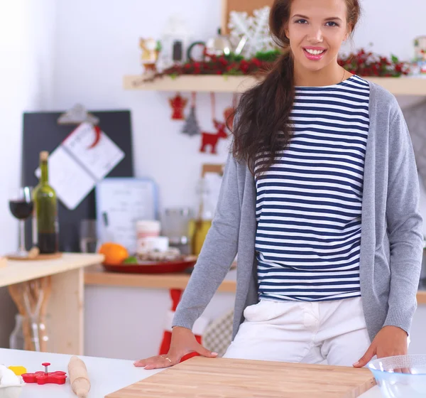 Jeune femme souriante dans la cuisine, isolée sur fond de Noël — Photo