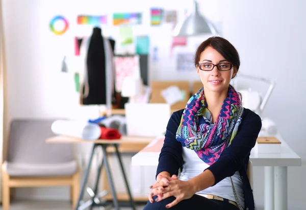 Beautiful fashion designer sitting at the desk in studio — Stock Photo, Image