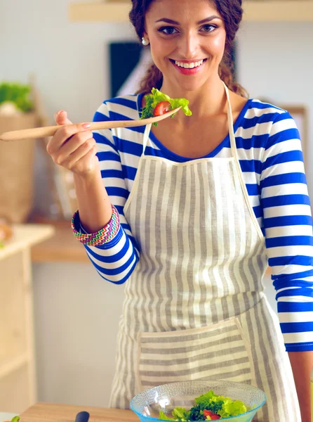 Young woman eating fresh salad in modern kitchen — Stock Photo, Image