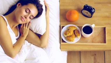 Genç ve güzel bir kadın yatakta yatıyor.