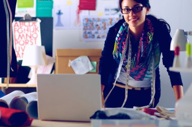 Güzel moda tasarımcısı stüdyoda duruyor.