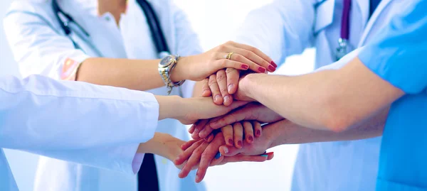 Doktorlar ve hemşireler tıbbi bir ekipte el ele tutuşuyorlar.