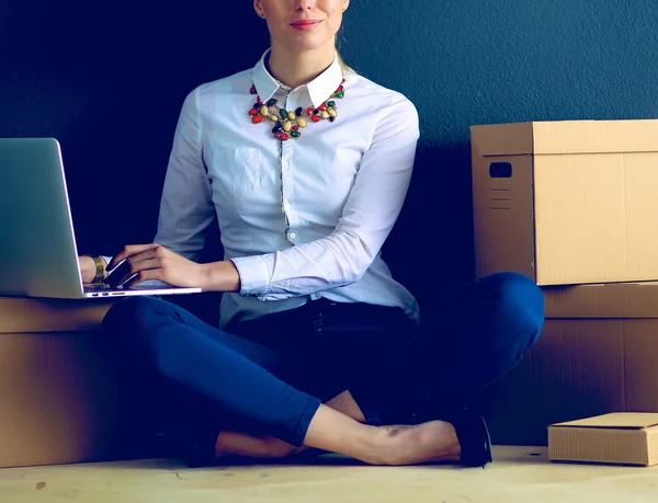 Frau sitzt auf dem Boden neben einer Schachtel mit Laptop — Stockfoto