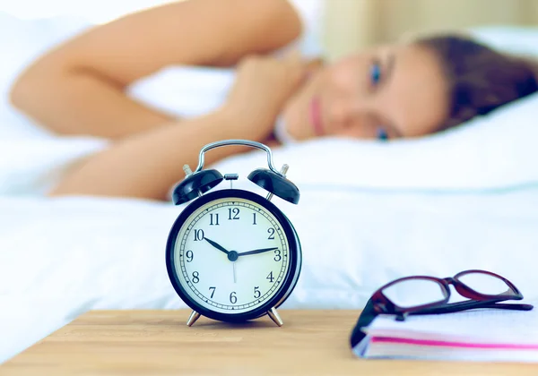 Une jeune femme éteint son réveil le matin — Photo