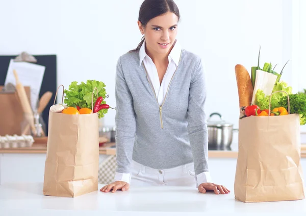 Woman with shopping bags in the kitchen at home, standing near desk — Stock Photo, Image