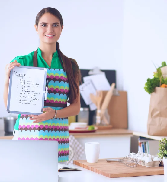 Donna in cucina a casa, in piedi vicino alla scrivania con cartella — Foto Stock