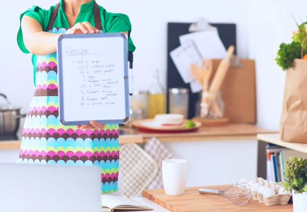 Glimlachende jonge vrouw in de keuken, geïsoleerd op de achtergrond — Stockfoto