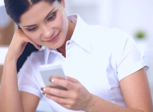 Donna d'affari che invia messaggi con smartphone seduto in ufficio — Foto Stock