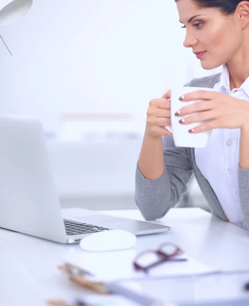 Junge Geschäftsfrau sitzt mit Tasse im Büro auf dem Schreibtisch — Stockfoto