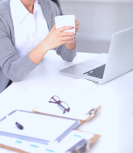 Young businesswoman sitting on the desk with cup in office — Stock Photo, Image