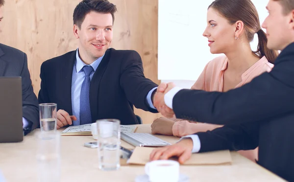 Zakenmensen handdruk, zitten aan de tafel — Stockfoto