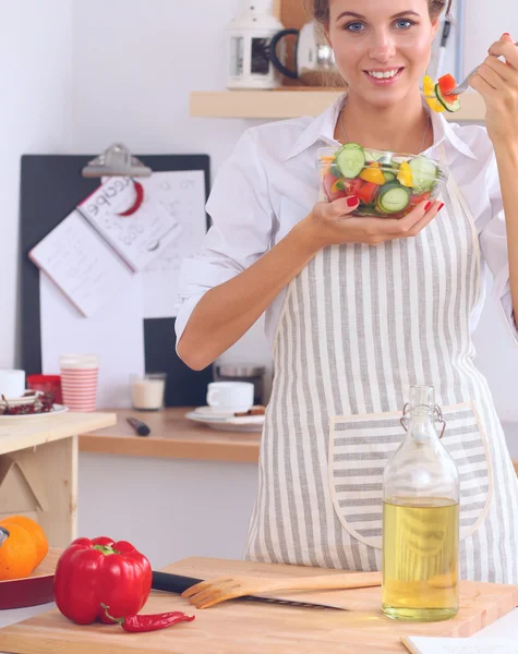 Młoda kobieta je świeżą sałatkę w nowoczesnej kuchni — Zdjęcie stockowe