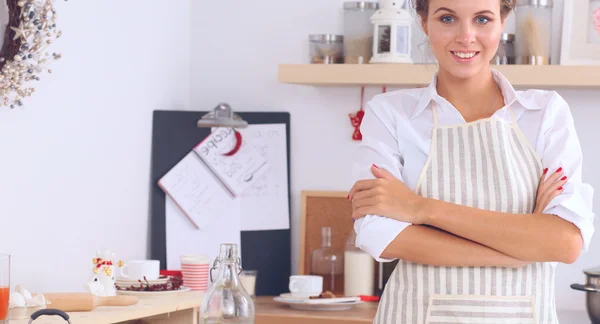 Glimlachende jonge vrouw in de keuken, geïsoleerd op kerst achtergrond — Stockfoto