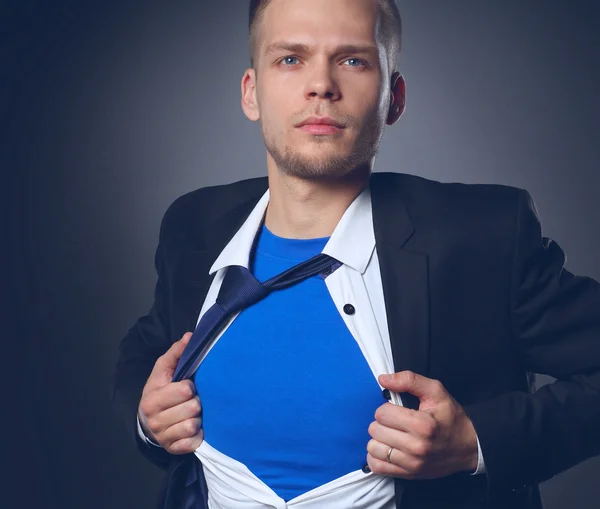 Молодой бизнесмен ведет себя как супергерой и разрывает рубашку, изолированный на сером фоне — стоковое фото