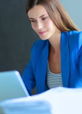 Elinde evrakları olan kadın masanın üstünde oturuyor..