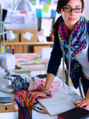 Güzel moda tasarımcısı stüdyoda duruyor.