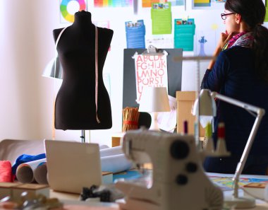 Güzel moda tasarımcısı stüdyoda duruyor.