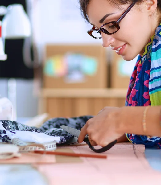 Moda tasarımcısı dikiş makinesinin yanında tekstil kesiyor. — Stok fotoğraf