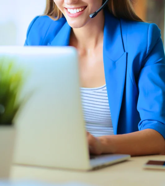 Porträtt av vacker affärskvinna som arbetar vid sitt skrivbord med headset och laptop.. — Stockfoto