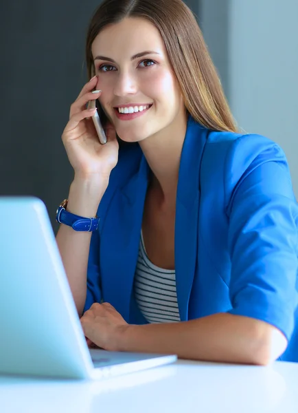 Portret van een jonge vrouw op telefoon achter een laptopcomputer. — Stockfoto