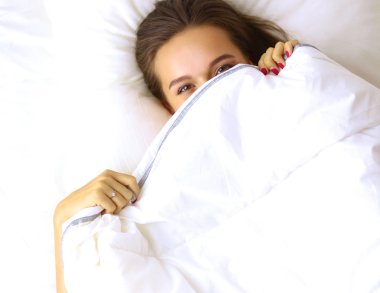 Genç ve güzel bir kadın yatakta yatıyor.