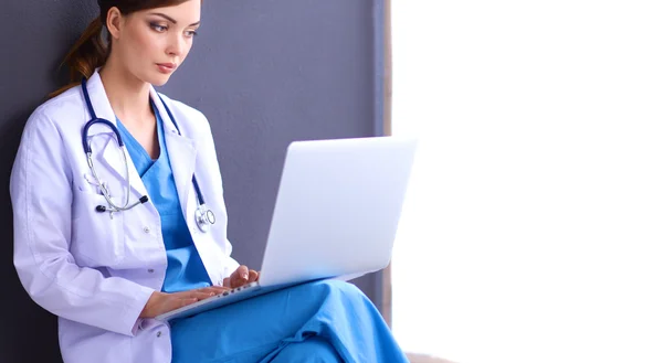 Médico femenino trabajando sentado sobre fondo gris — Foto de Stock