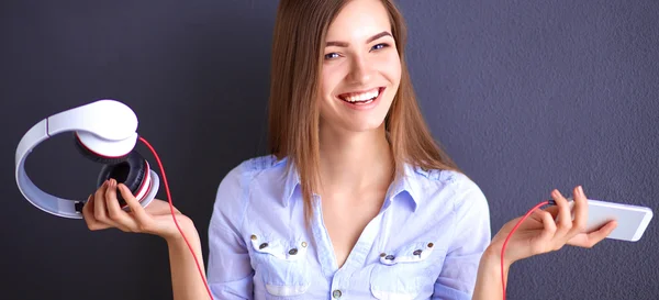 Fille souriante avec écouteurs assis sur le sol près du mur — Photo