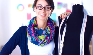 Gülümseyen moda tasarımcısı ofiste mankenin yanında duruyor.