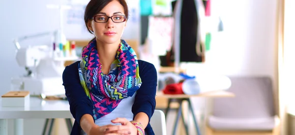 Beautiful fashion designer sitting at the desk in studio — Stock Photo, Image