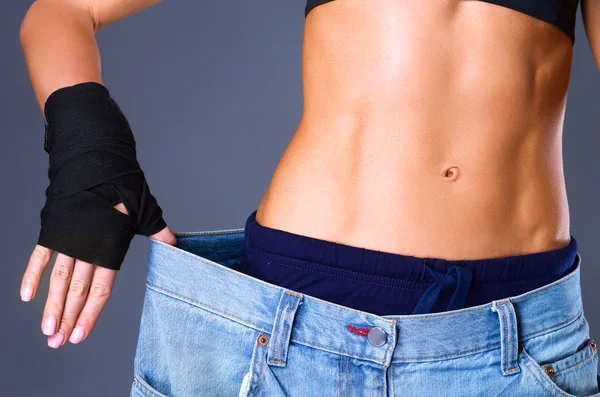 Junge Fitness-Frau zeigt, dass ihre alten Jeans — Stockfoto