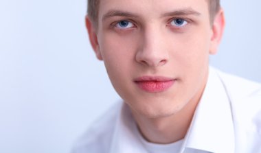 Gri arka plan üzerinde oturan gülümseyen genç adam portresi