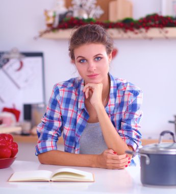 Mutfakta gülümseyen genç bir kadın, Noel arkaplanında soyutlanmış.