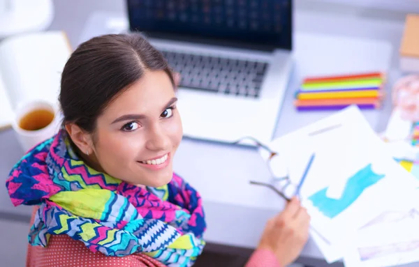 Young attractive female fashion designer working at office desk, drawing while talking on mobile — Stock Photo, Image