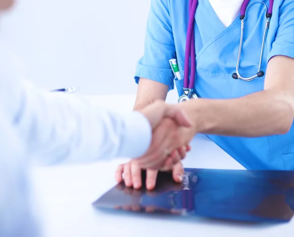 Médico apertando as mãos com um paciente, sentado na mesa no escritório — Fotografia de Stock