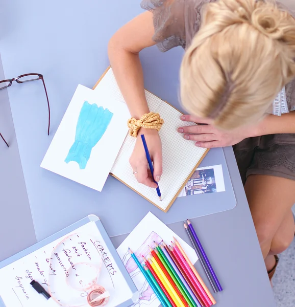 Joven y atractiva diseñadora de moda femenina trabajando en el escritorio de la oficina, dibujando mientras habla en el móvil — Foto de Stock