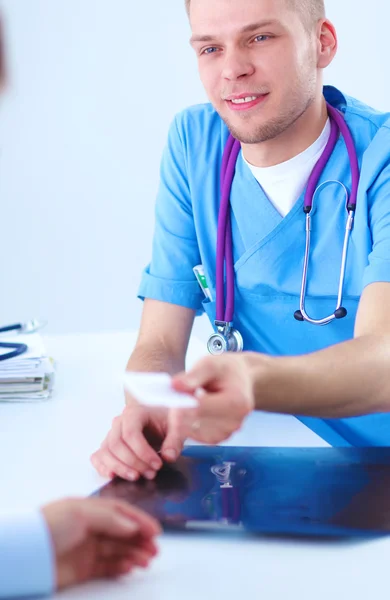 Portret van een lachende mannelijke arts met laptop aan het bureau in medisch kantoor — Stockfoto