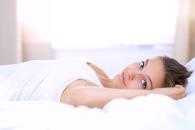 Yatakta rahat ve mutlu bir şekilde yatan güzel bir genç kadın.