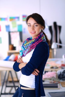 Güzel moda tasarımcısı stüdyoda duruyor.