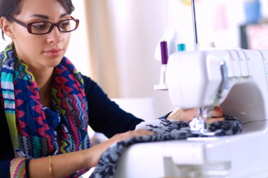 Çalışırken dikiş diken genç bir kadın.