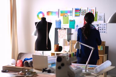 Güzel moda tasarımcısı stüdyoda duruyor.