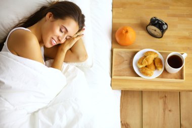 Genç ve güzel bir kadın yatakta yatıyor.