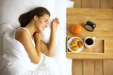 Genç ve güzel bir kadın yatakta yatıyor.