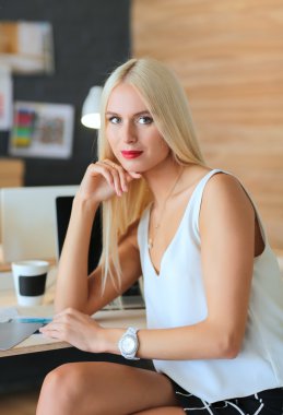 Moda tasarımcıları stüdyoda çalışıyor. Masanın üzerinde oturuyorlar.