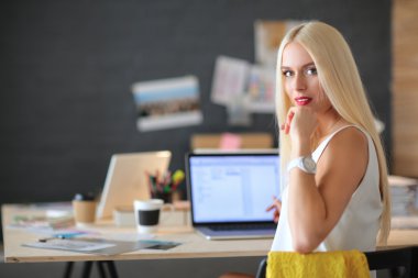 Moda tasarımcıları stüdyoda çalışıyor. Masanın üzerinde oturuyorlar.